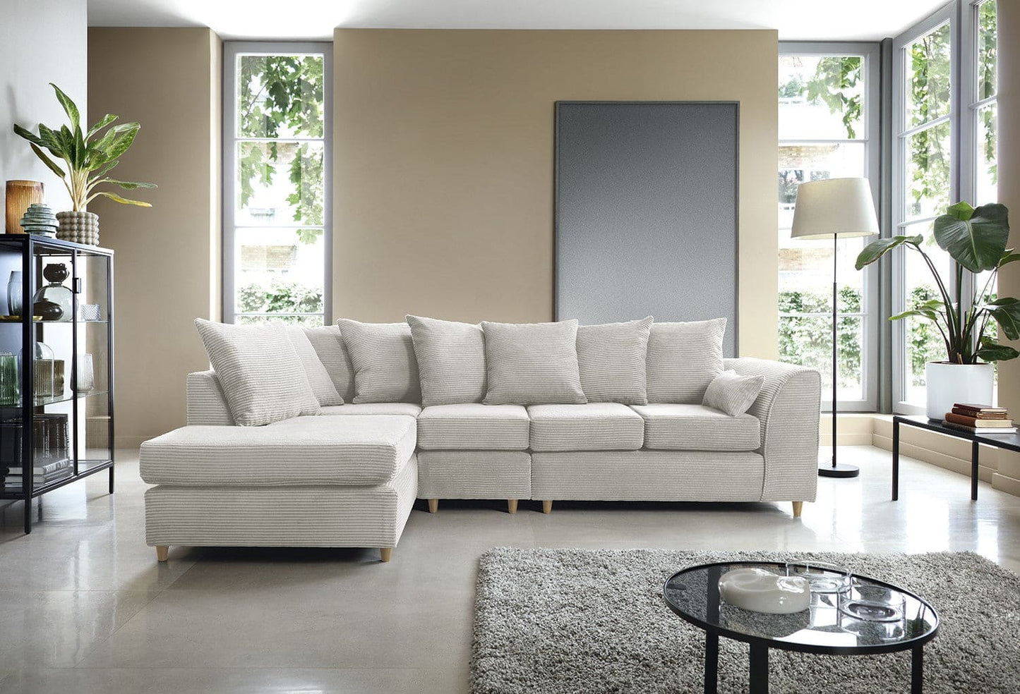 Modern living room with a gray sectional sofa, coffee table, and decorative plants.