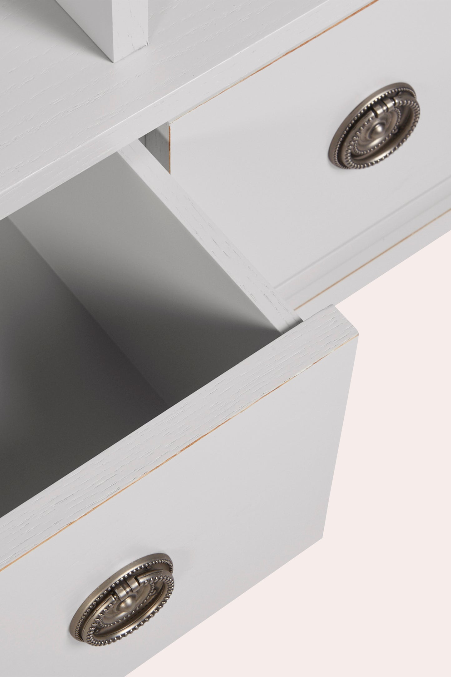 Close-up of a light grey drawer with metallic knobs on a white background