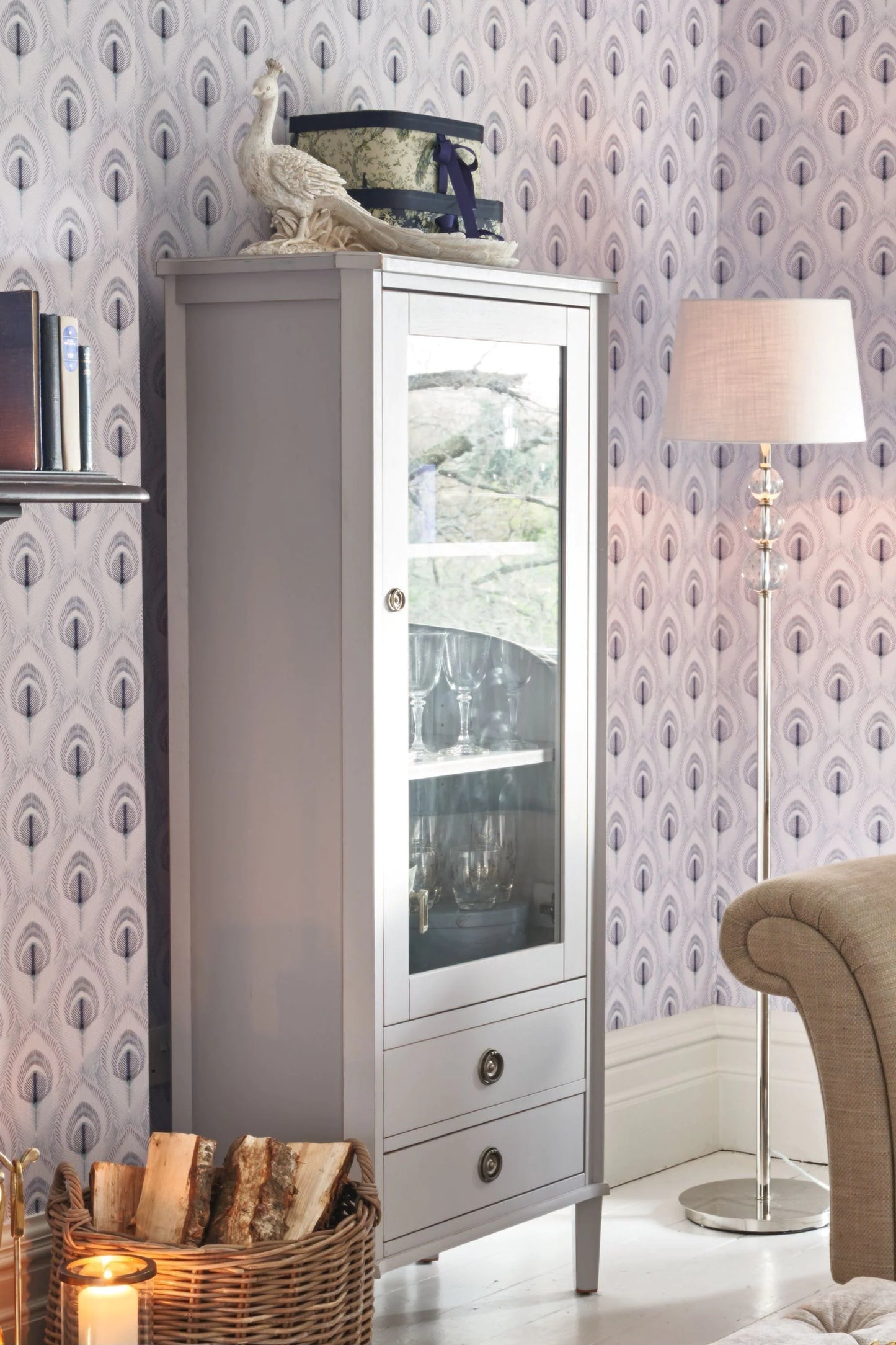 White cabinet with glass door against a patterned wallpaper wall.