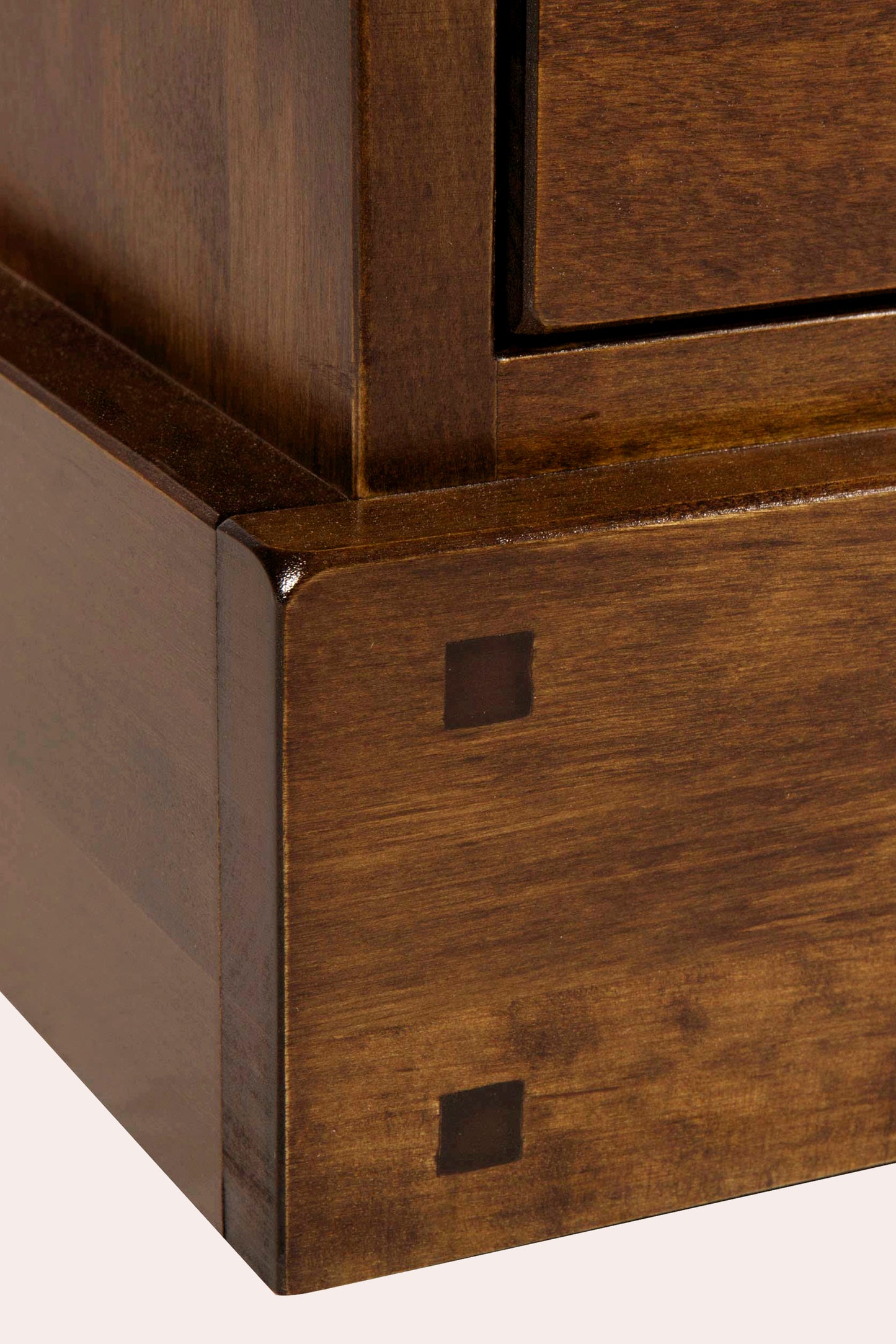 Close-up of a wooden TV stand corner with a small square cutout.