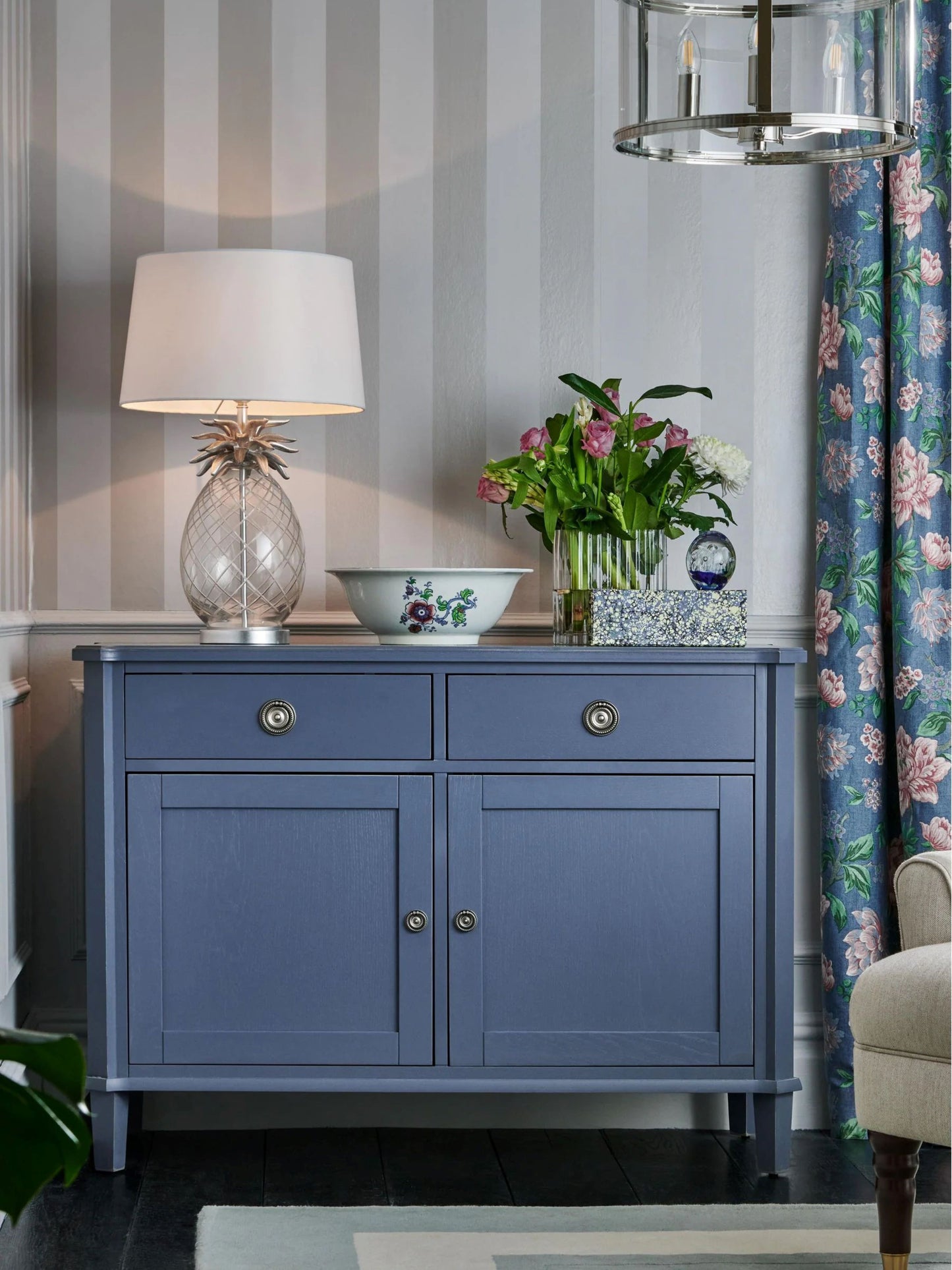 Blue cabinet with decorative items against a striped wall