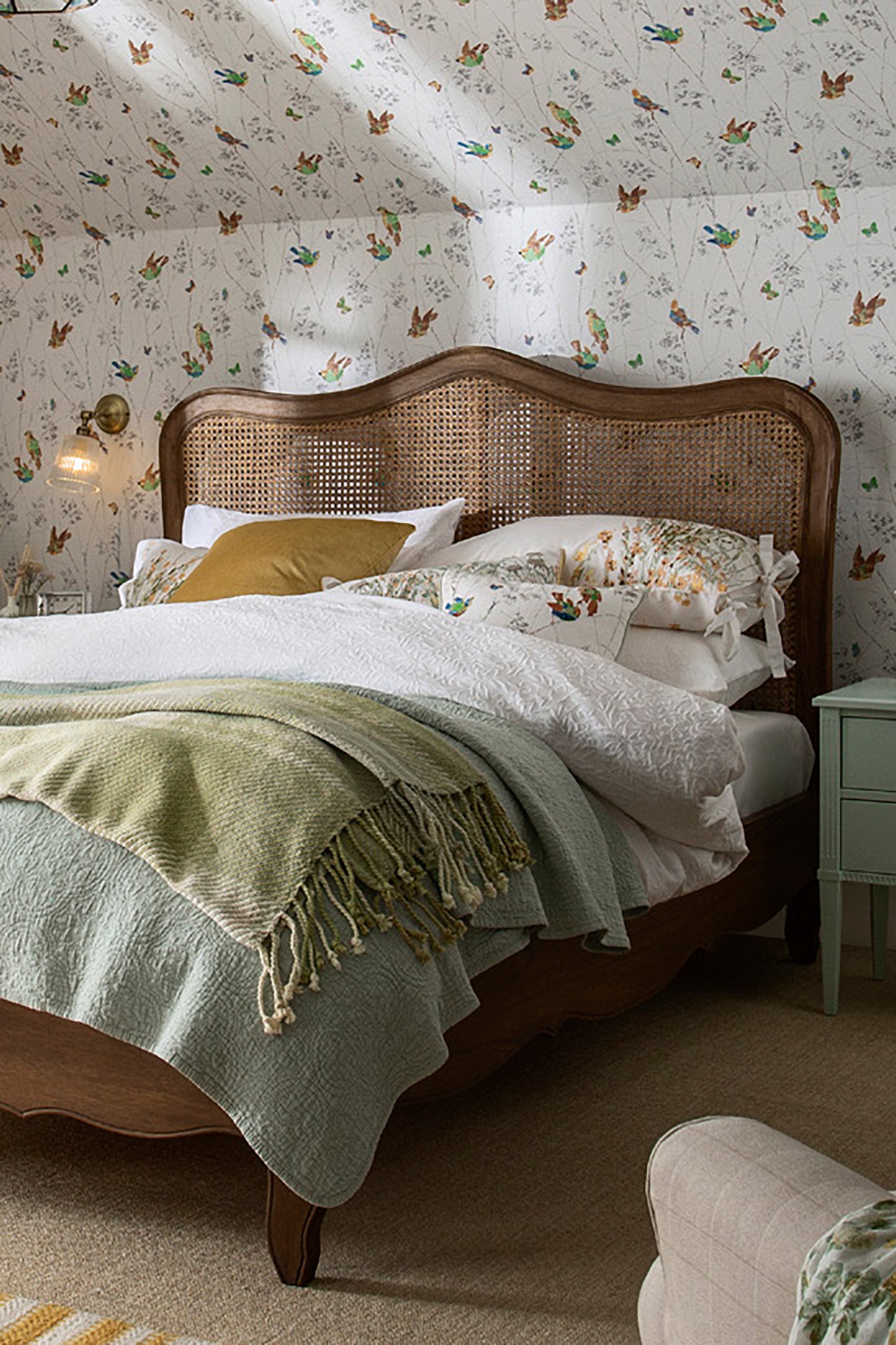 Bedroom with floral wallpaper, wooden bed, and green blanket