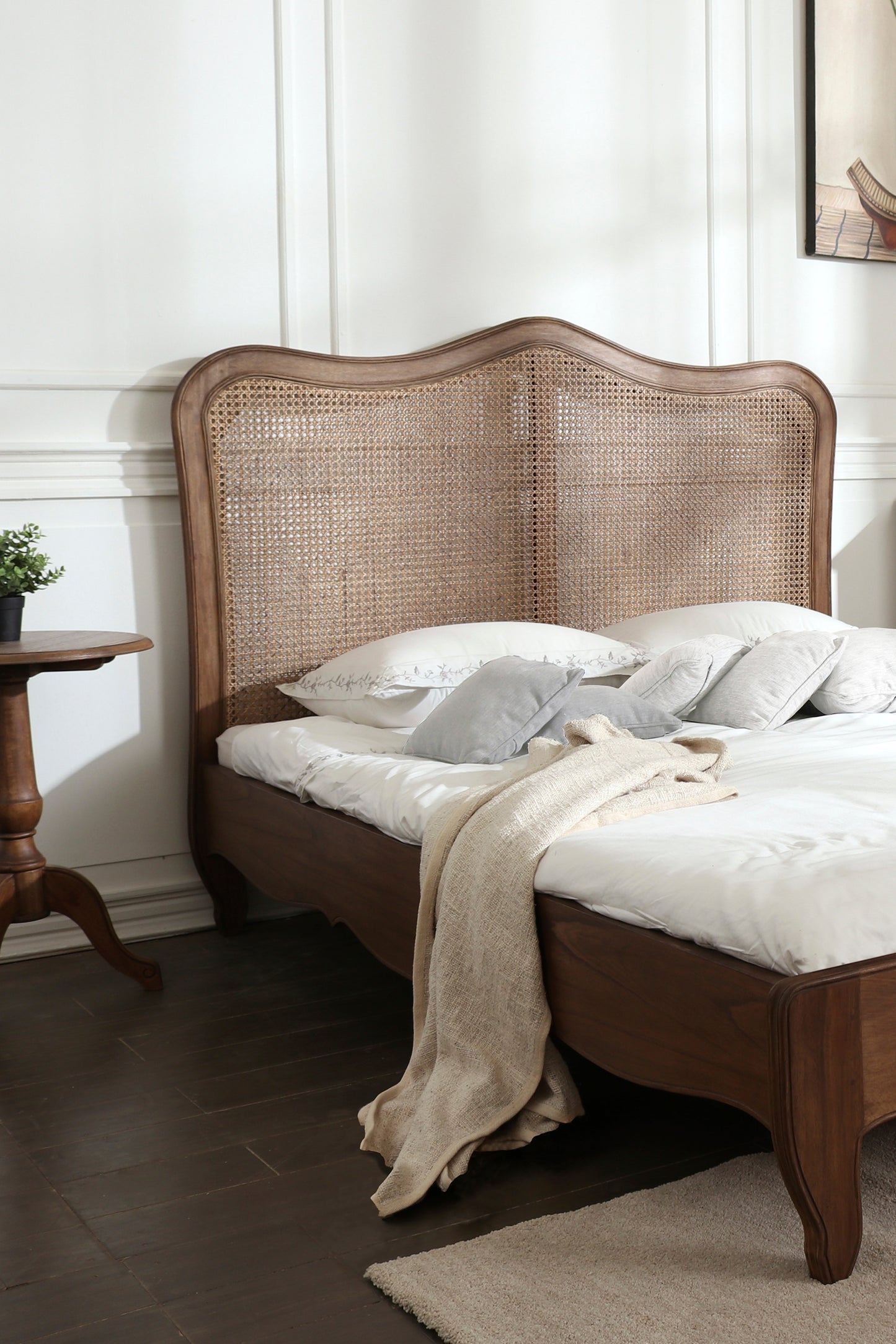 Wooden bed with wicker headboard and white bedding in a bedroom setting.