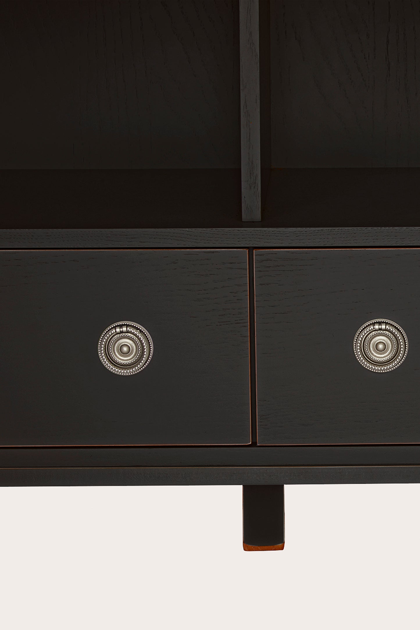 Close up of black drawers of a black bookcase with decorative silver knobs on a white background