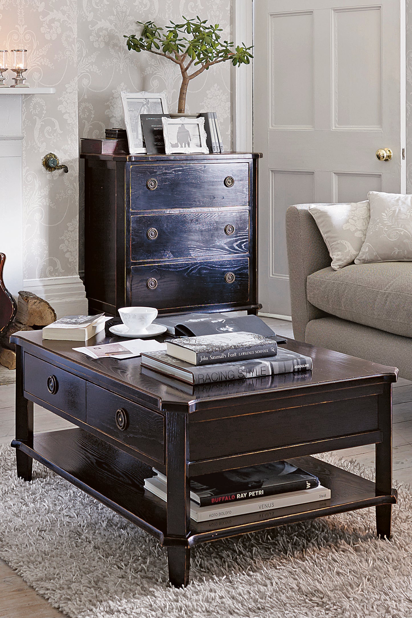 Dark wood coffee table with books and a cup in a living room setting.