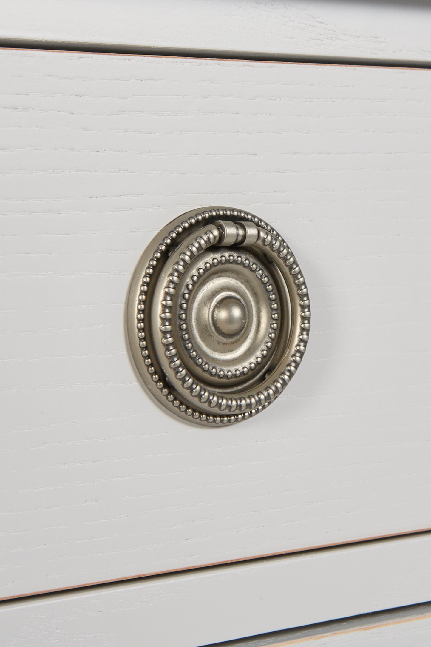 Close-up of a decorative cabinet knob on a white wooden surface