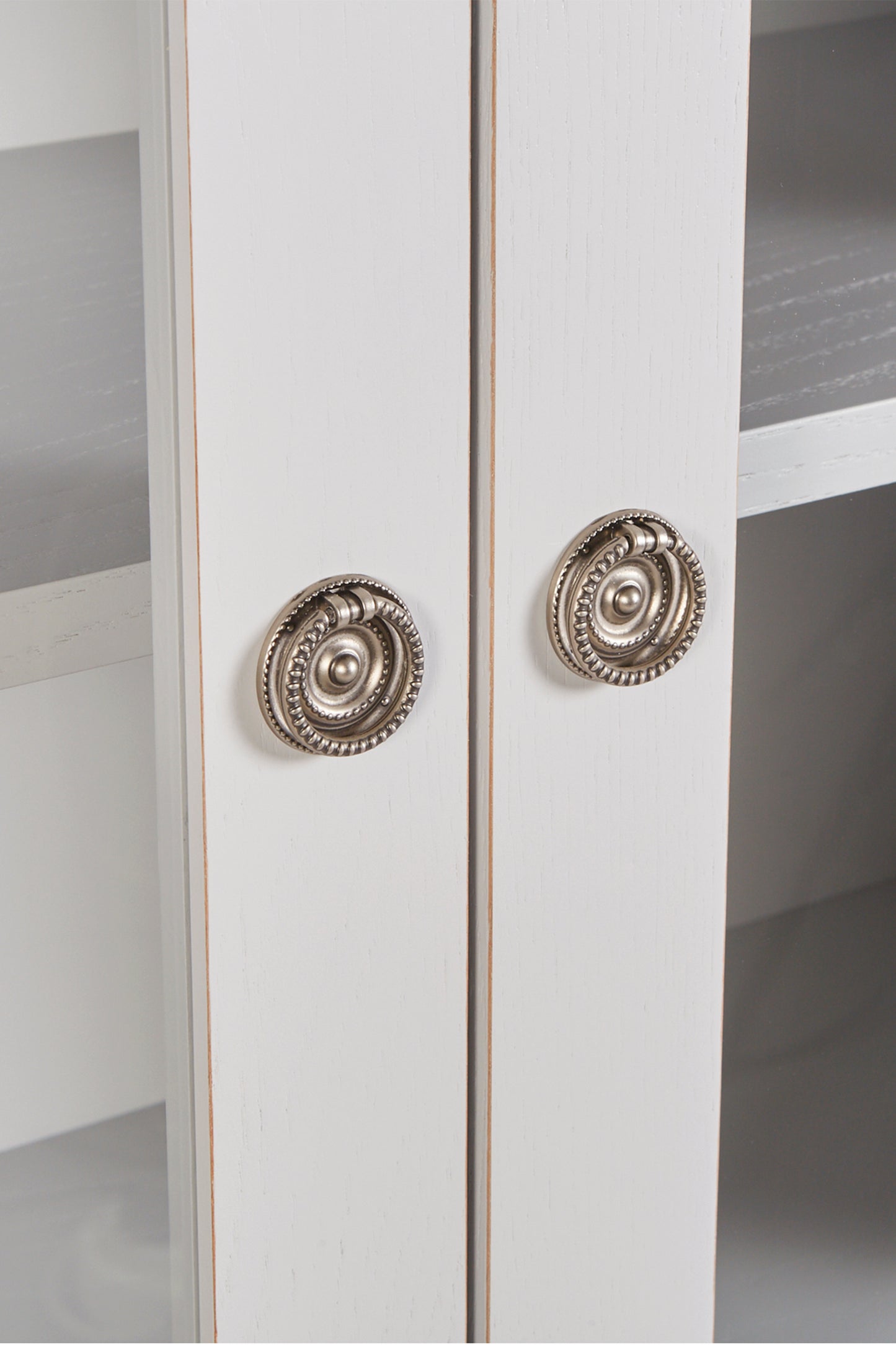 White cabinet with decorative silver handles on a white background