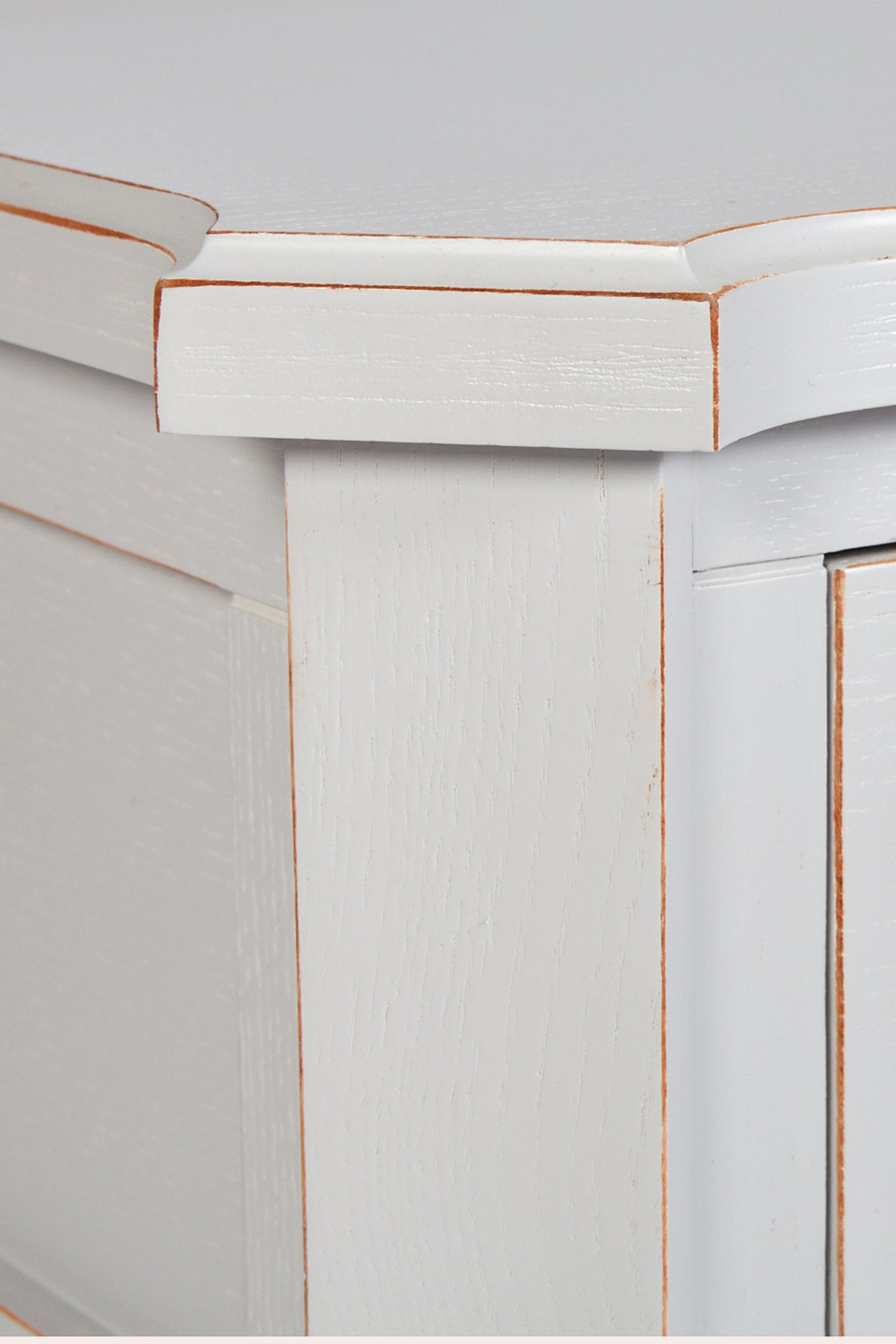 Close-up of a white cabinet with decorative molding on a light gray background