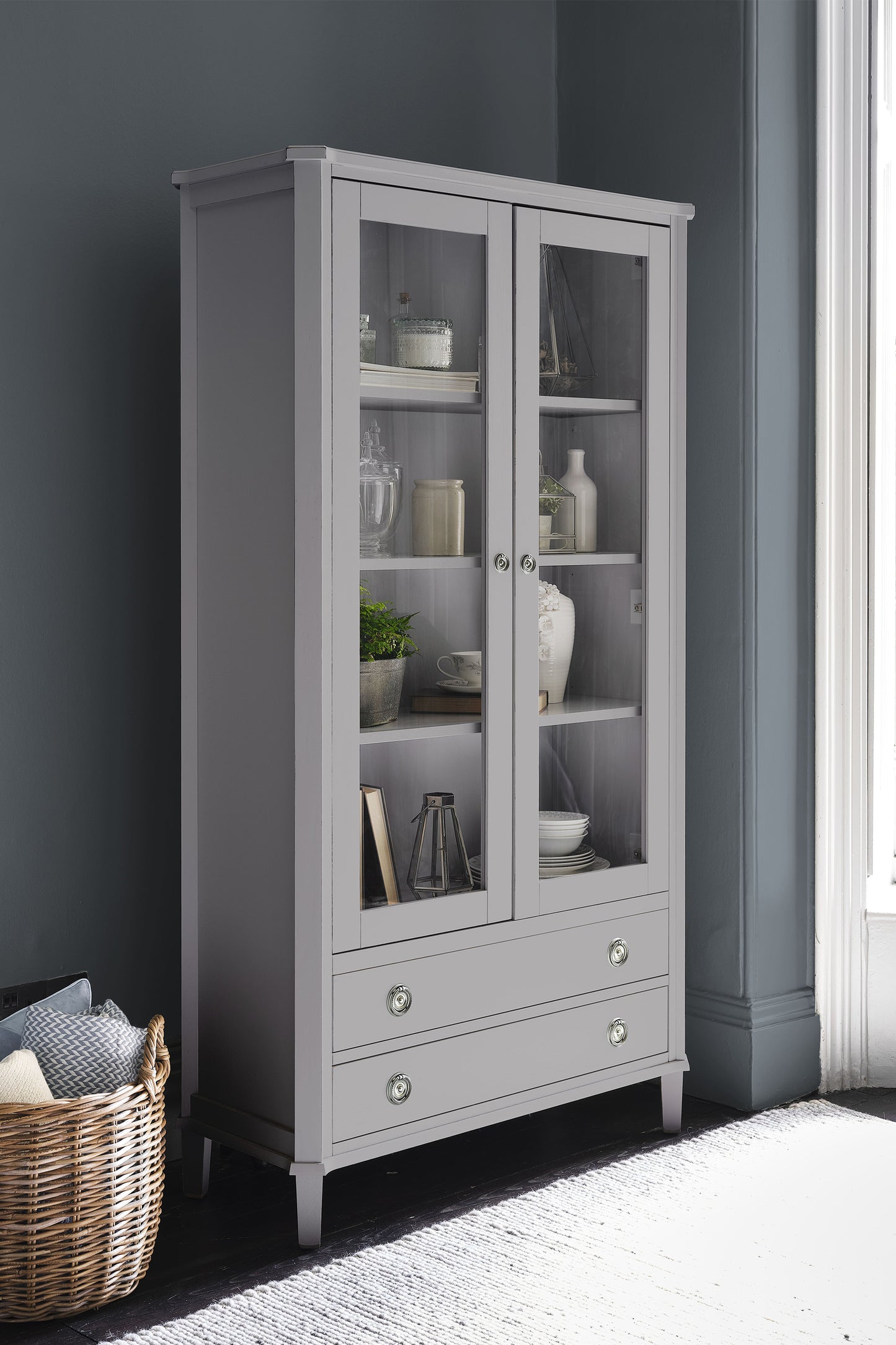 Gray display cabinet with glass doors against a dark gray wall.