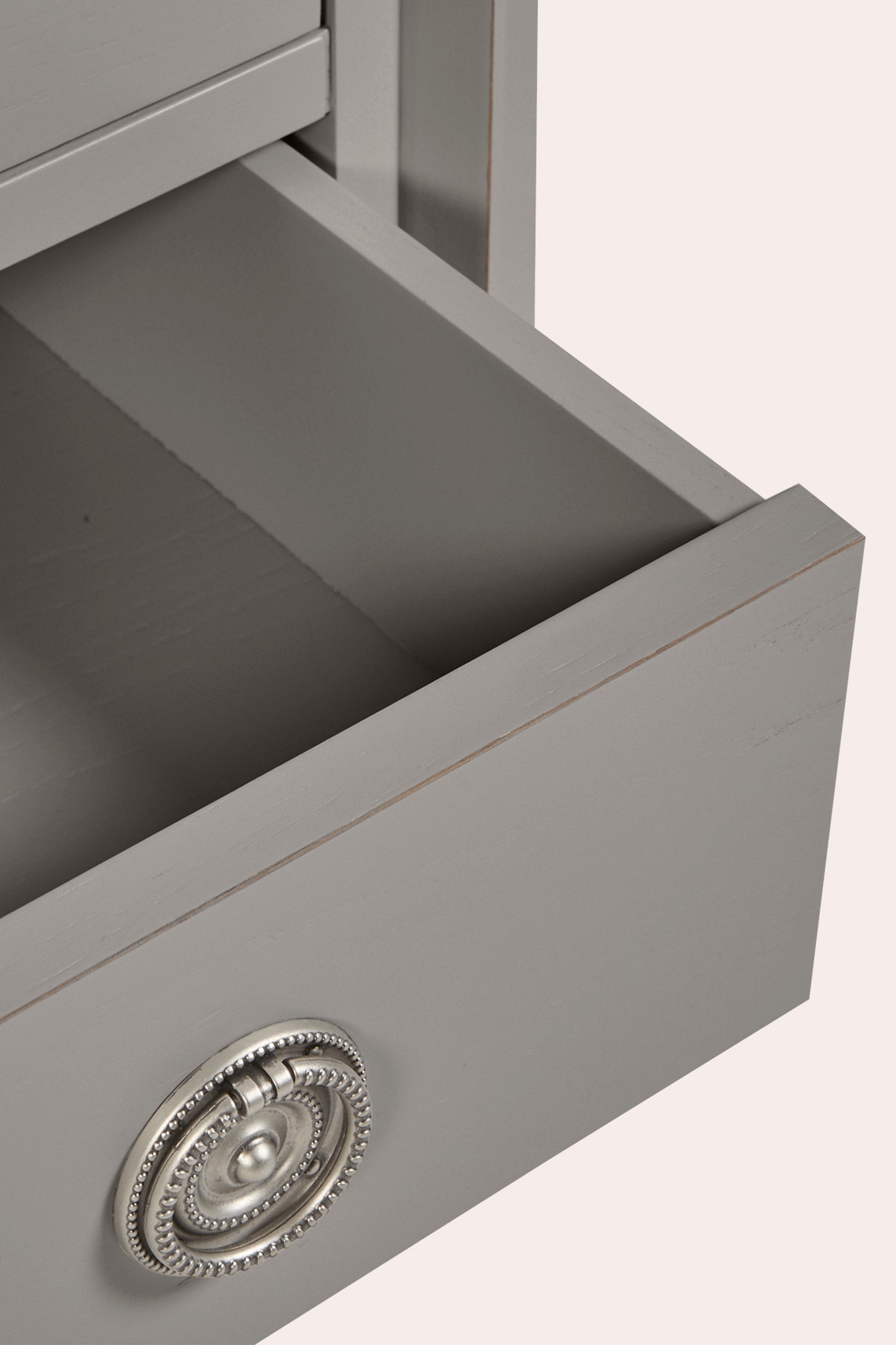 Gray drawer with decorative handle on a light pink background