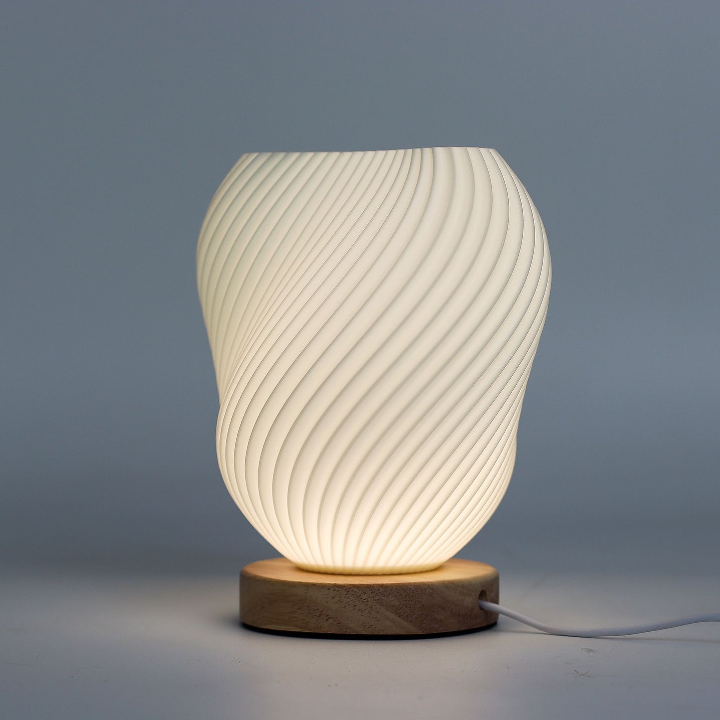 Decorative table lamp with ribbed design and wooden base on a gray background