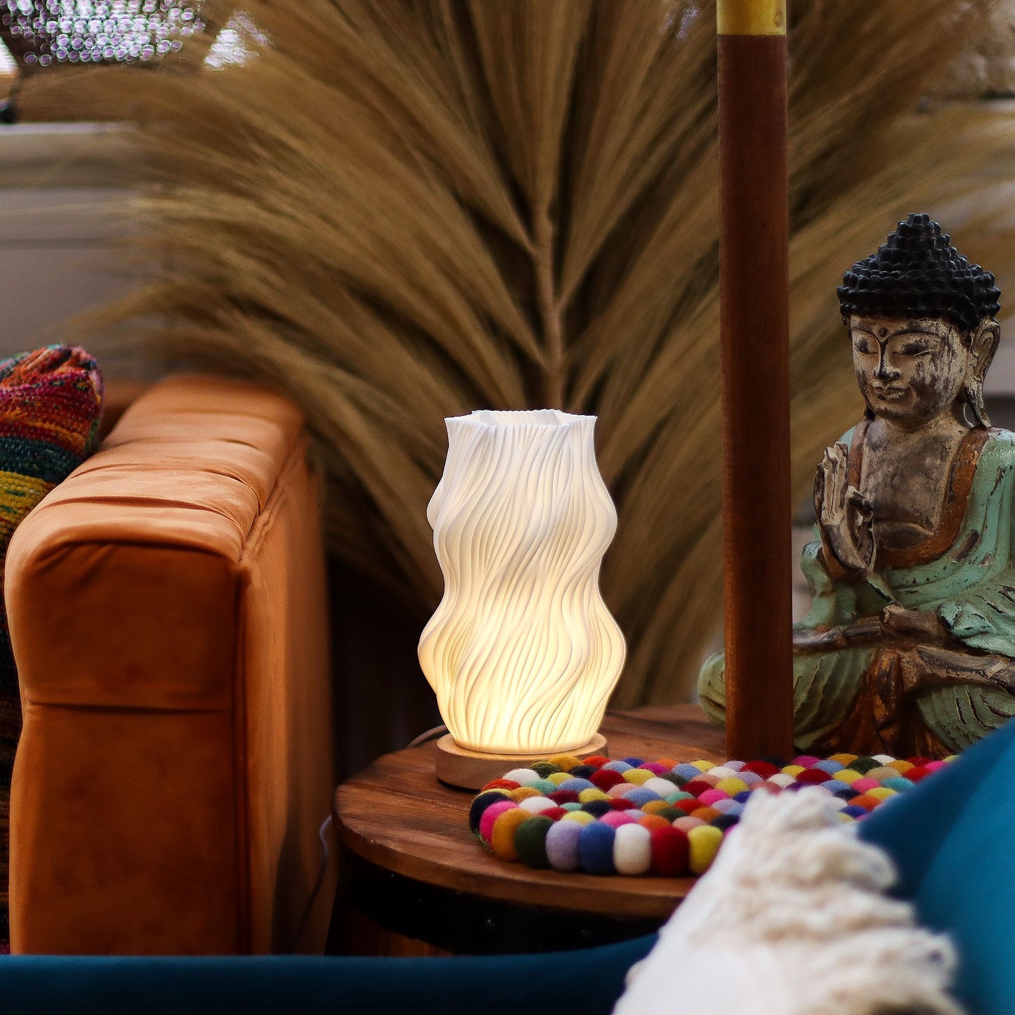 Decorative lamp on a small table with a statue and colorful items in the background