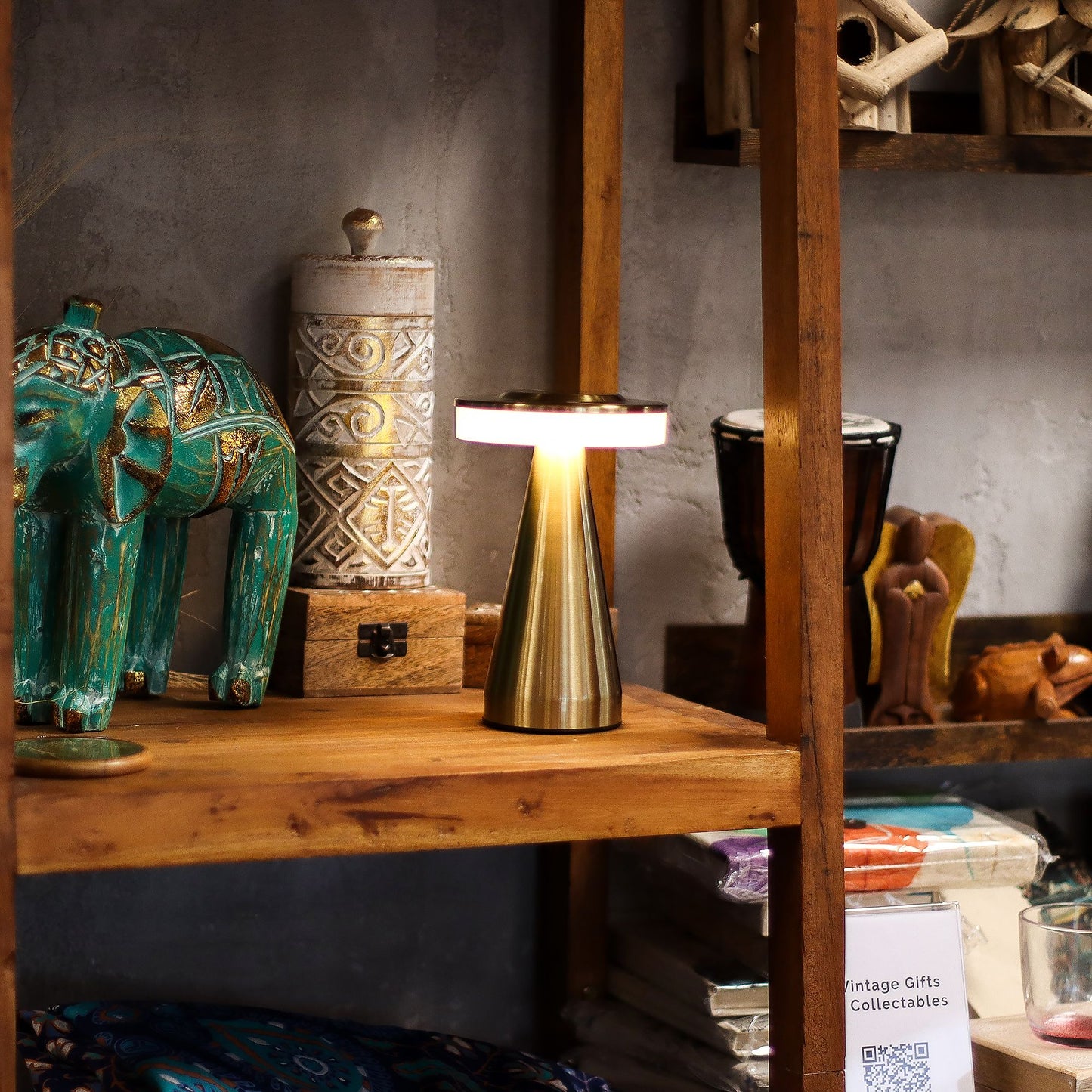Gold touch lamp on a wooden shelf with decorative items in a rustic setting