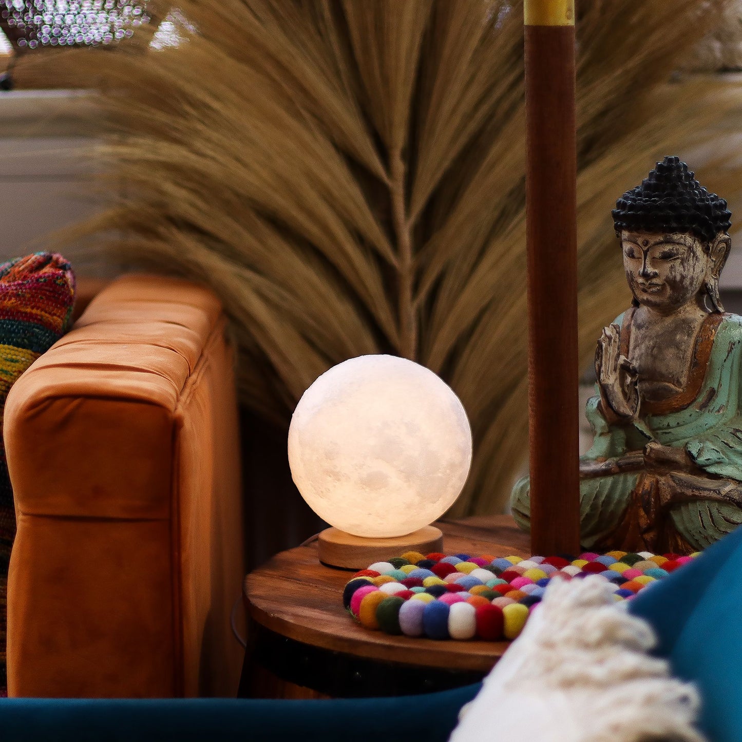 Decorative lamp on a small table with a statue and colorful items in a cozy room.