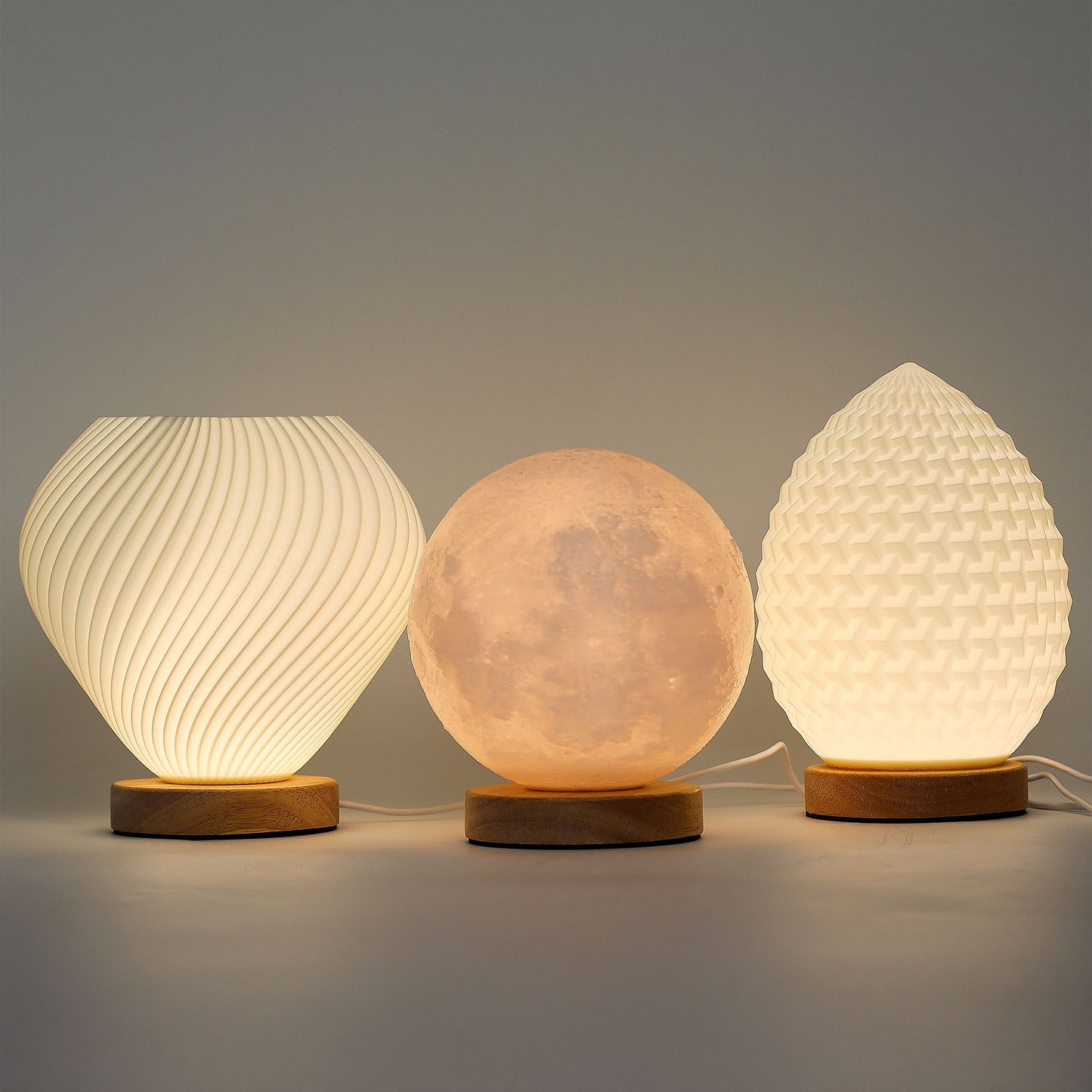 Three textured table lamps with wooden bases on a gray background