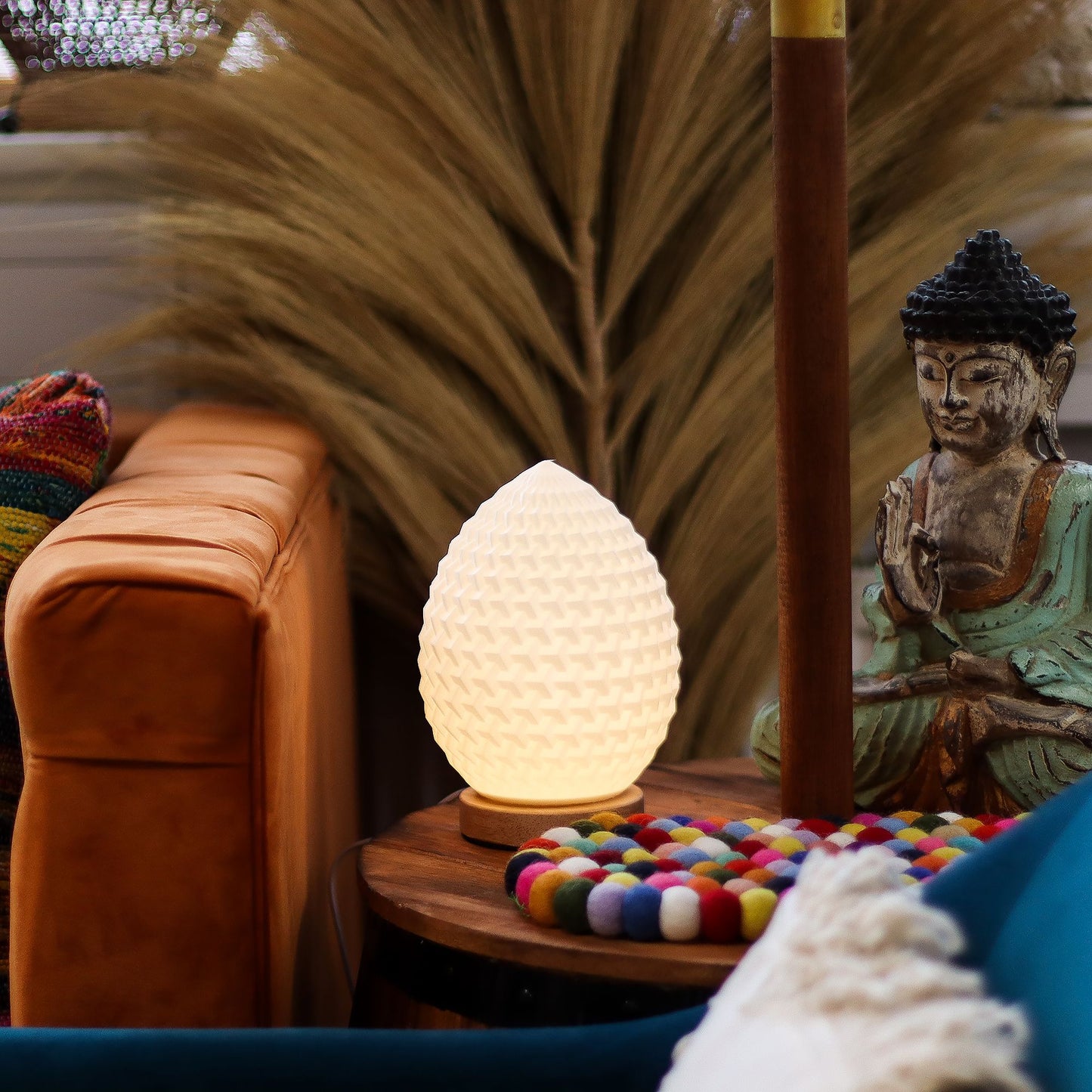 Decorative lamp on a table with a Buddha statue and colorful items in a cozy setting