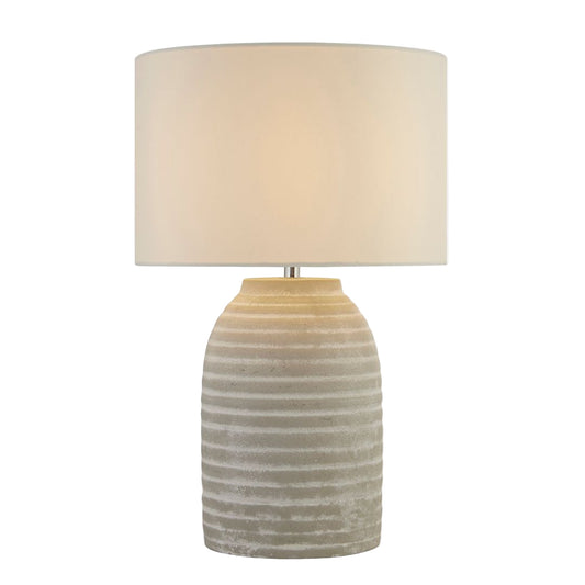 Table lamp with textured ceramic base and beige fabric shade on a white background
