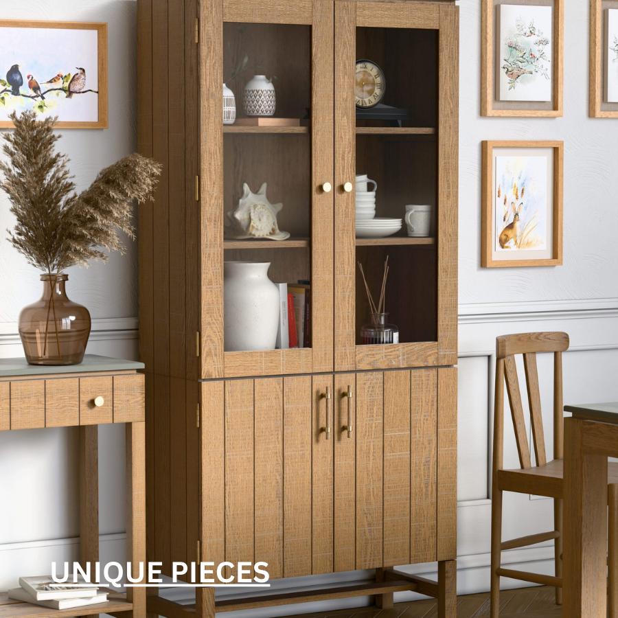 Light brown display cabinet with two doors below and shelving on top with glass panelled doors. Crafted from solid oak and oak veneer with a gently distressed white-washed finish