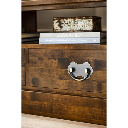Wooden drawer with a unique handle and books on a shelf above.