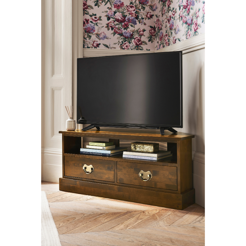 Wooden TV stand with a television and decor in a room with floral wallpaper.