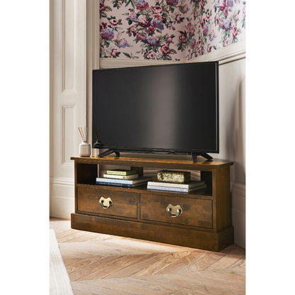 Wooden TV stand with a television and decor in a room with floral wallpaper.
