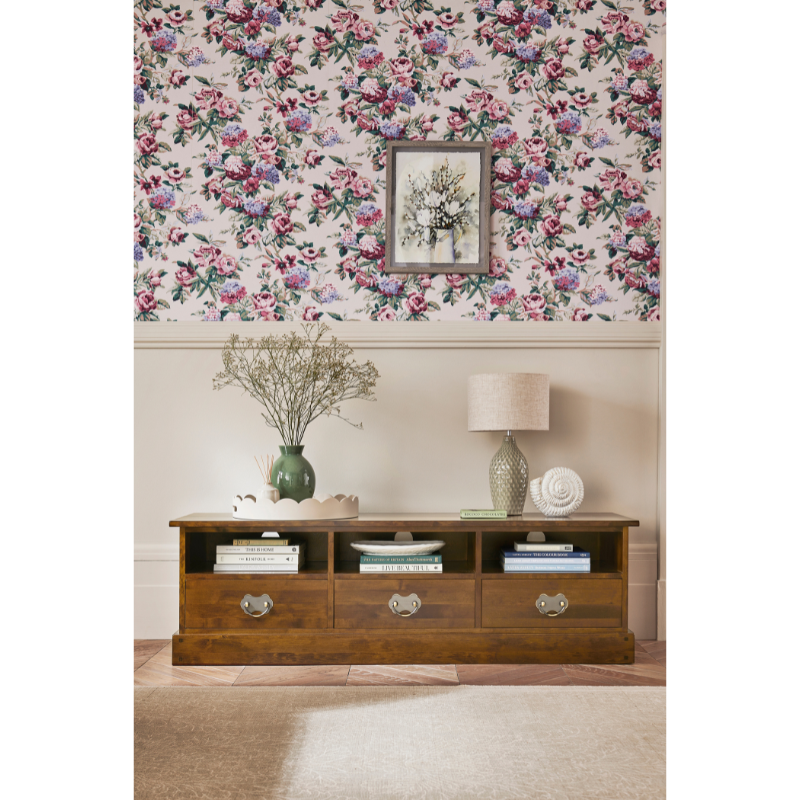 Wooden cabinet with decorative items against a floral wallpaper background.