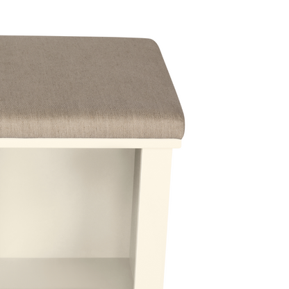 A close up corner view of a white shoe storage bench with multiple compartments and a cushioned seat on a plain background.