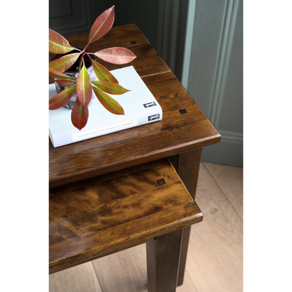 Wooden table with a laptop and plant on a wooden floor.