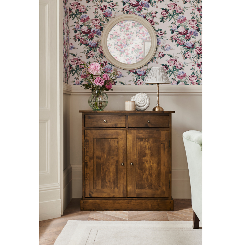 Wooden sideboard cabinet with floral wallpaper and decor in the background