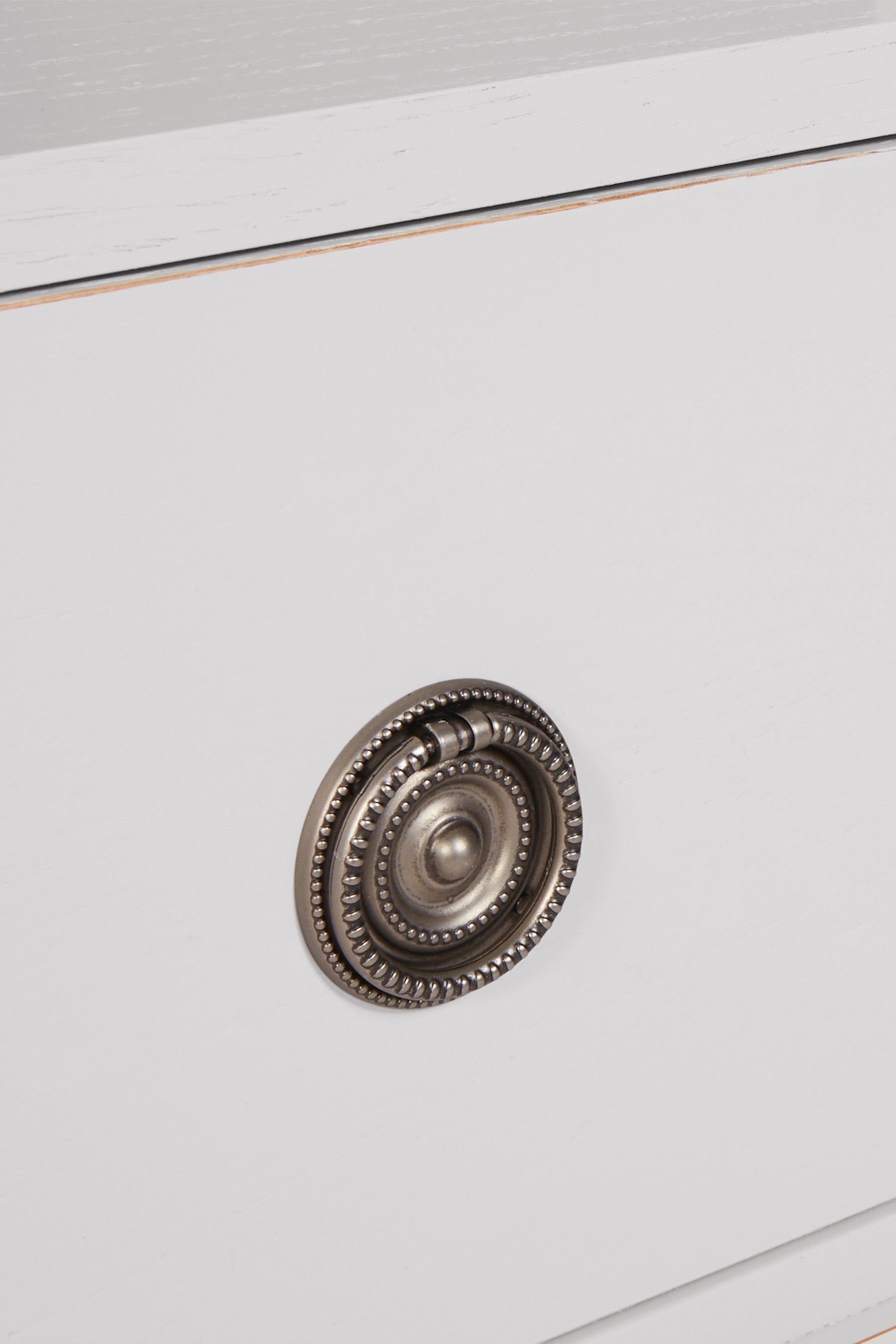 Close-up of a decorative metal knob on a light grey bookcase