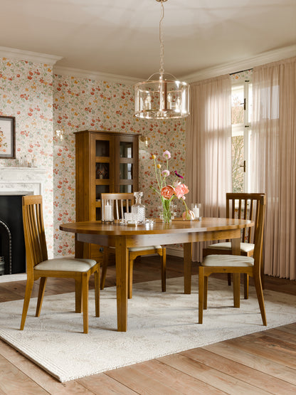 Dining room with wooden furniture and floral wallpaper.