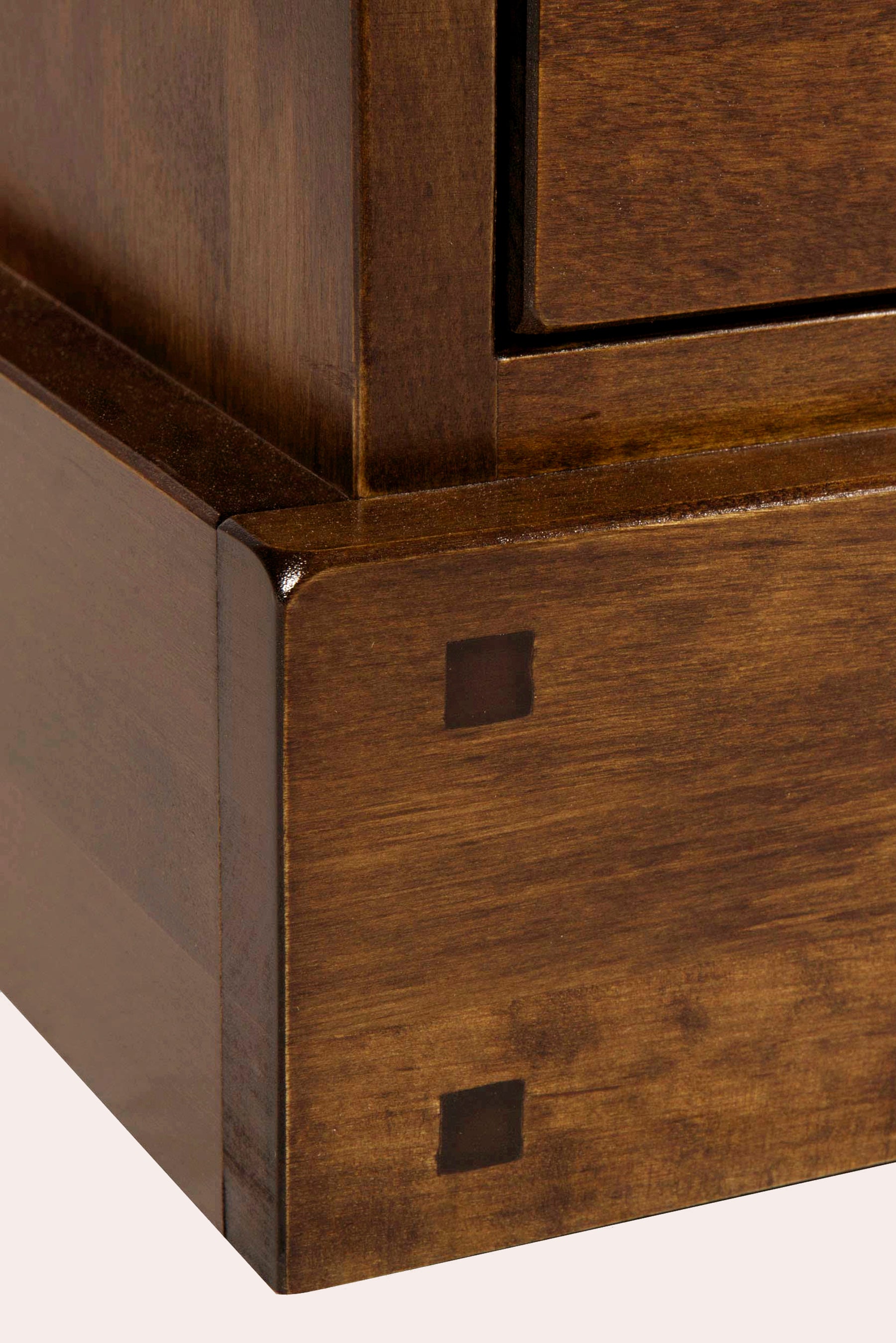 Close-up of a wooden cabinet corner with a small square hole.