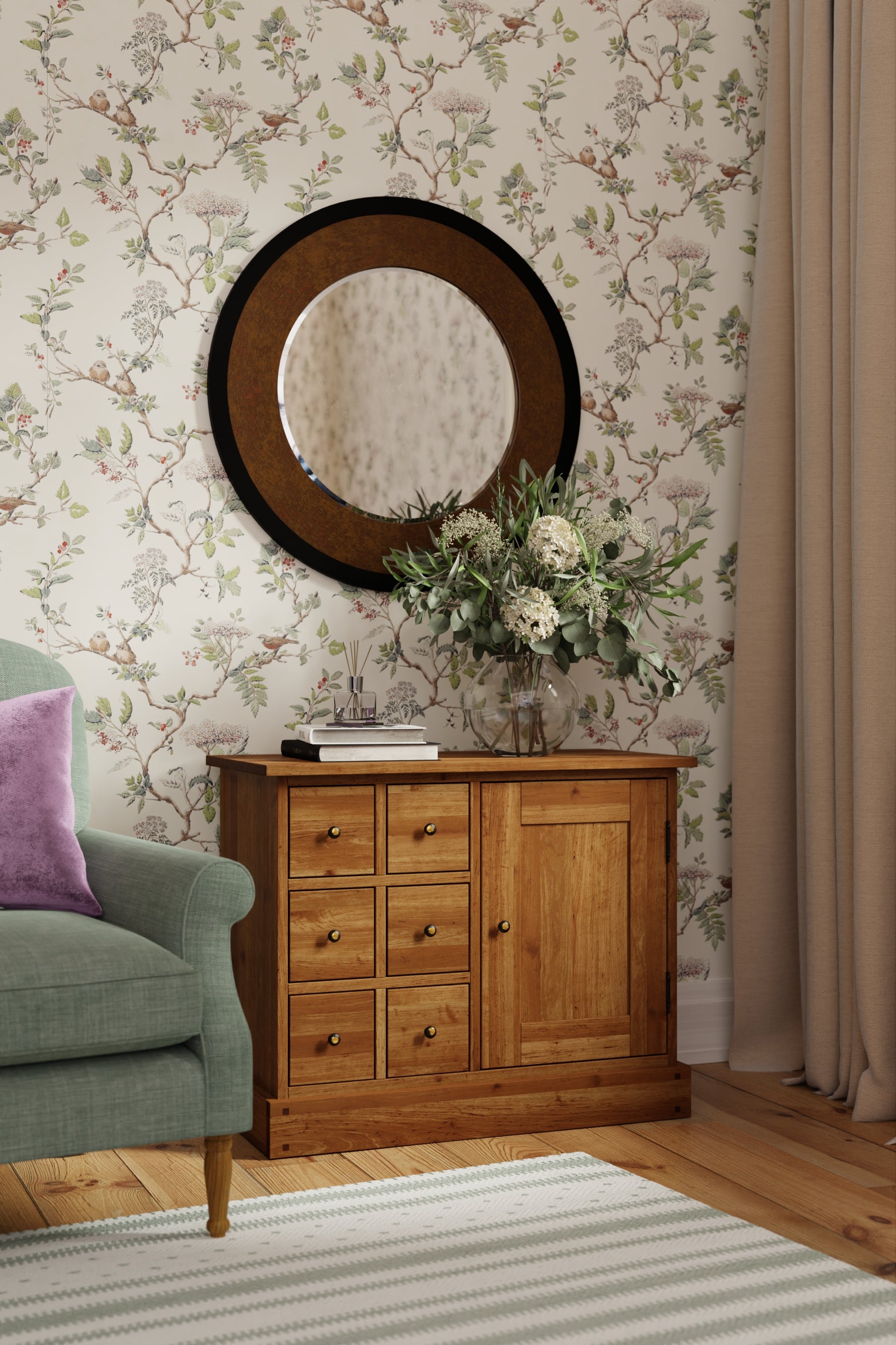 A honey-coloured wooden sideboard with one door and six drawers, with a simple traditional design with floral wallpaper and mirror in a room.