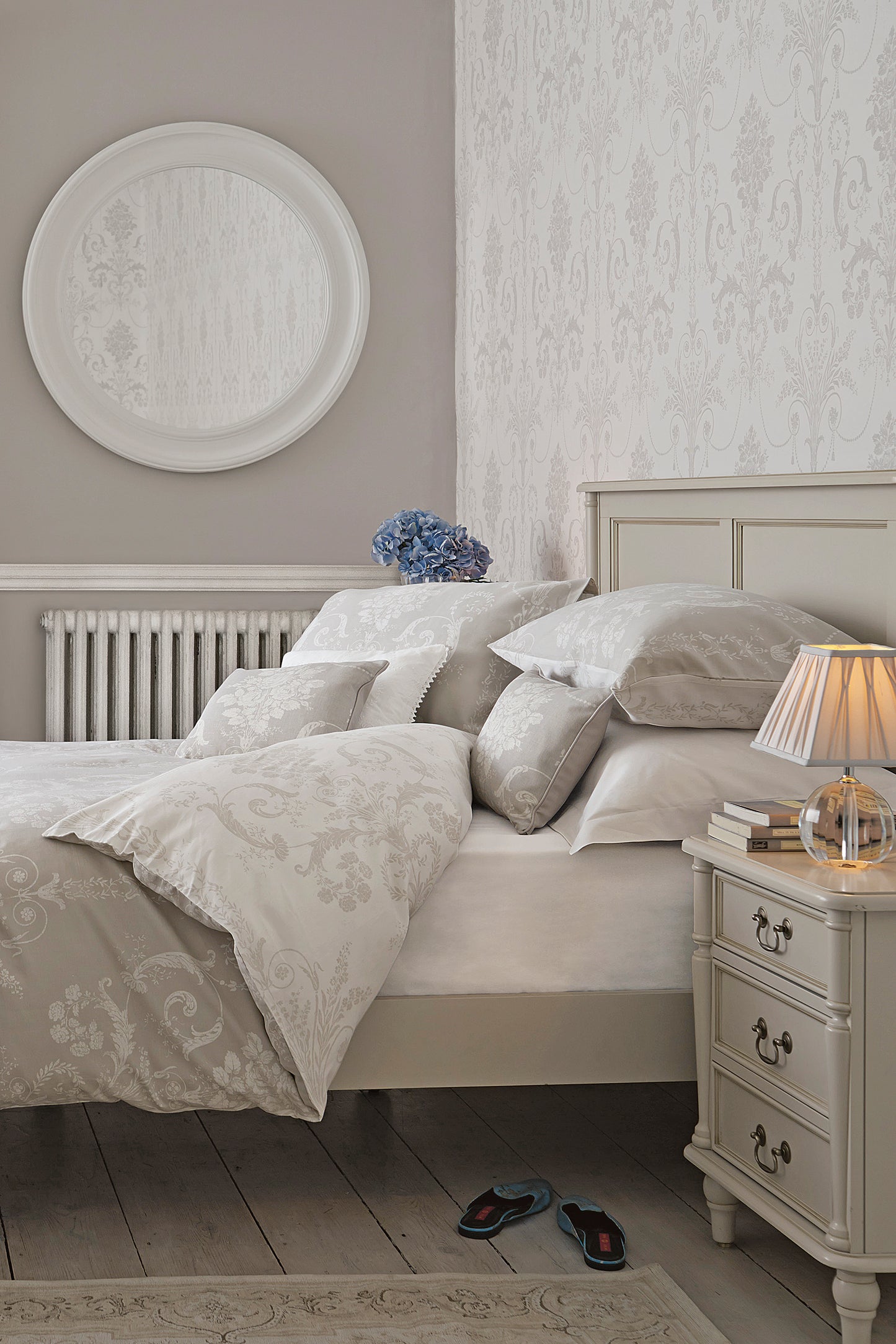 A right-hand angle of a Dove grey wooden bed frame with a headboard and footboard, with bedding and additional accessories.