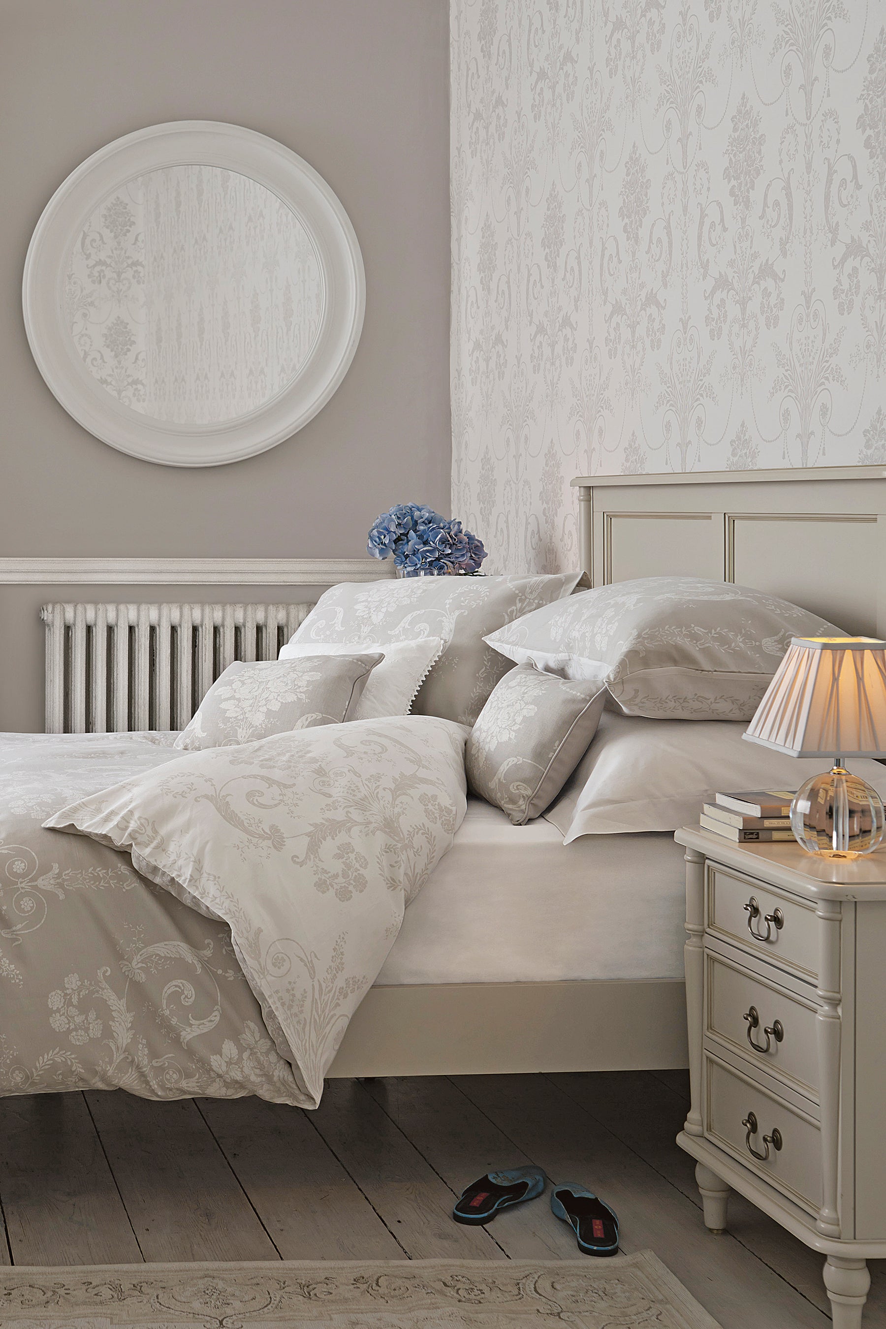 A right-hand angle of a Dove grey wooden bed frame with a headboard and footboard, with bedding and additional accessories.