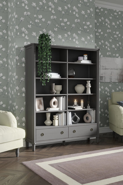Dark grey bookcase with decorative items against a floral wallpapered wall.