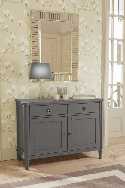 Gray bathroom vanity with mirror and decorative items against floral wallpaper.