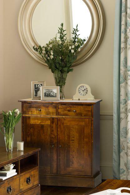 Wooden sideboard with vases, photos, and clock against a neutral wall.