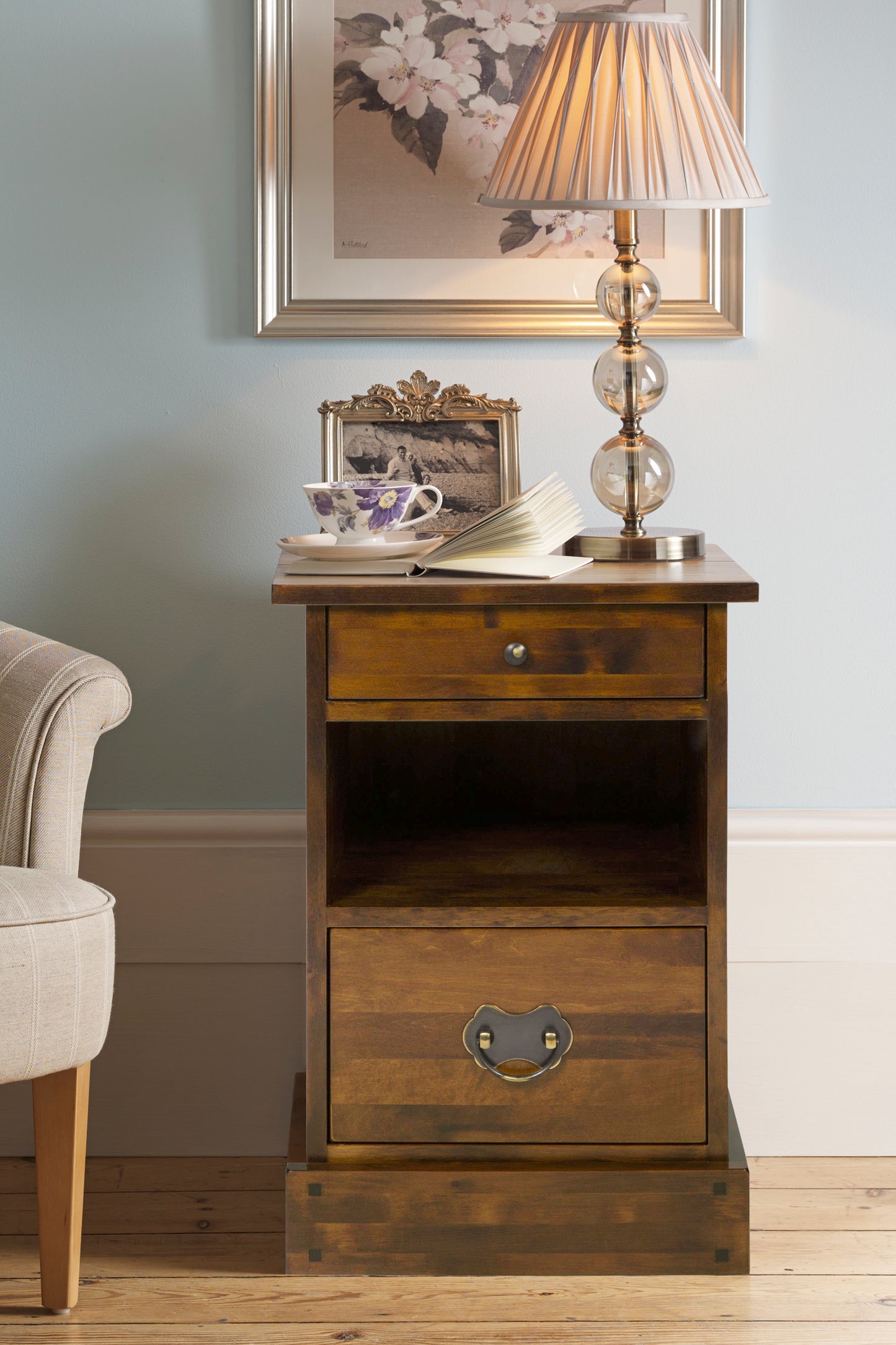 Wooden side table with lamp and cup in a room setting
