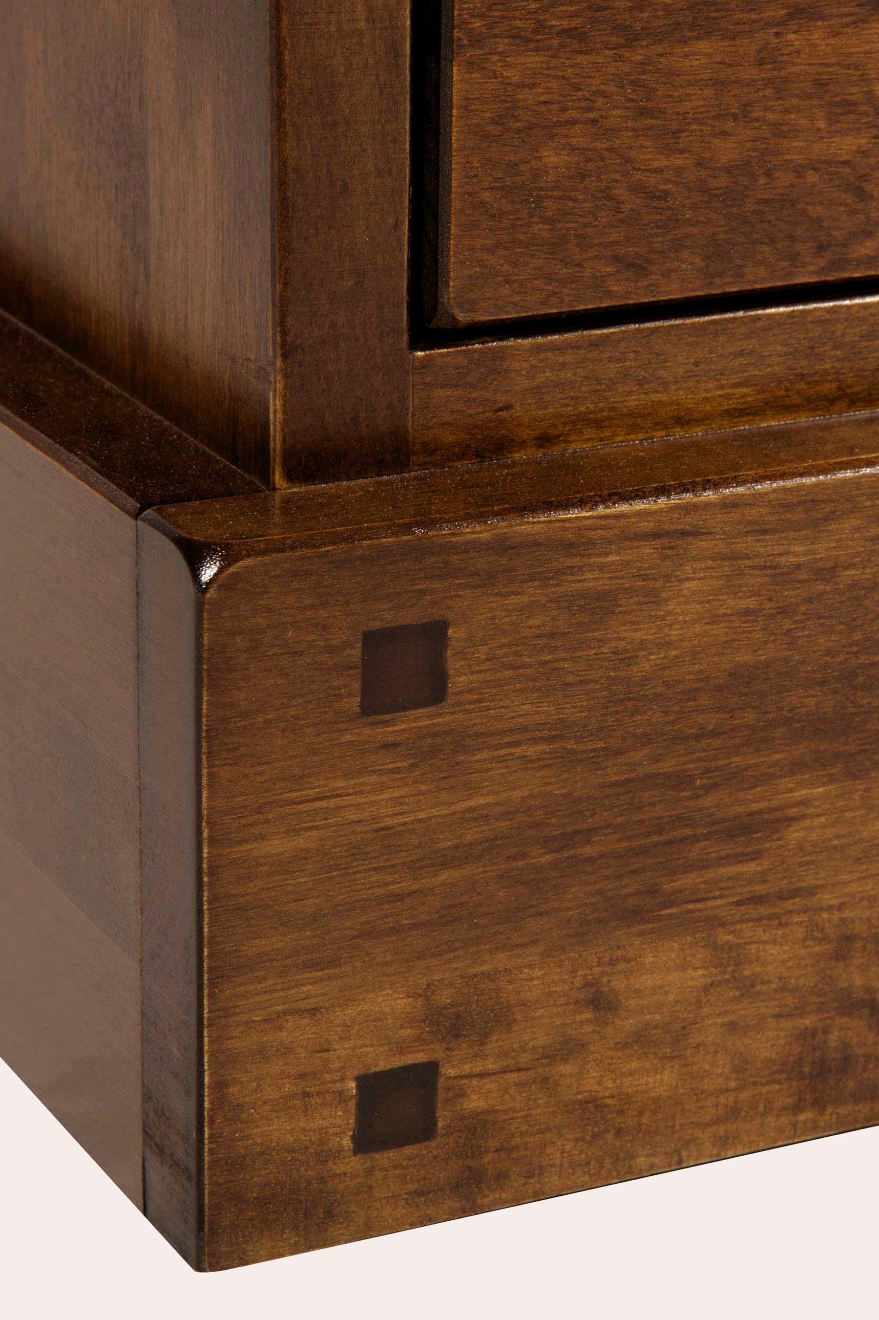 Close-up of a wooden cabinet corner with a metallic accent.