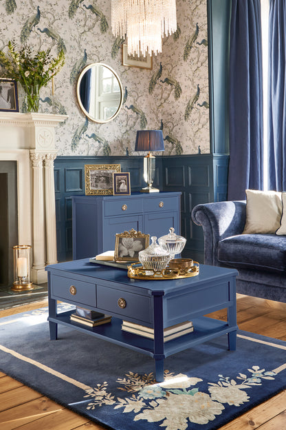 Living room with blue furniture, including a coffee table and sideboard, and decorative elements.