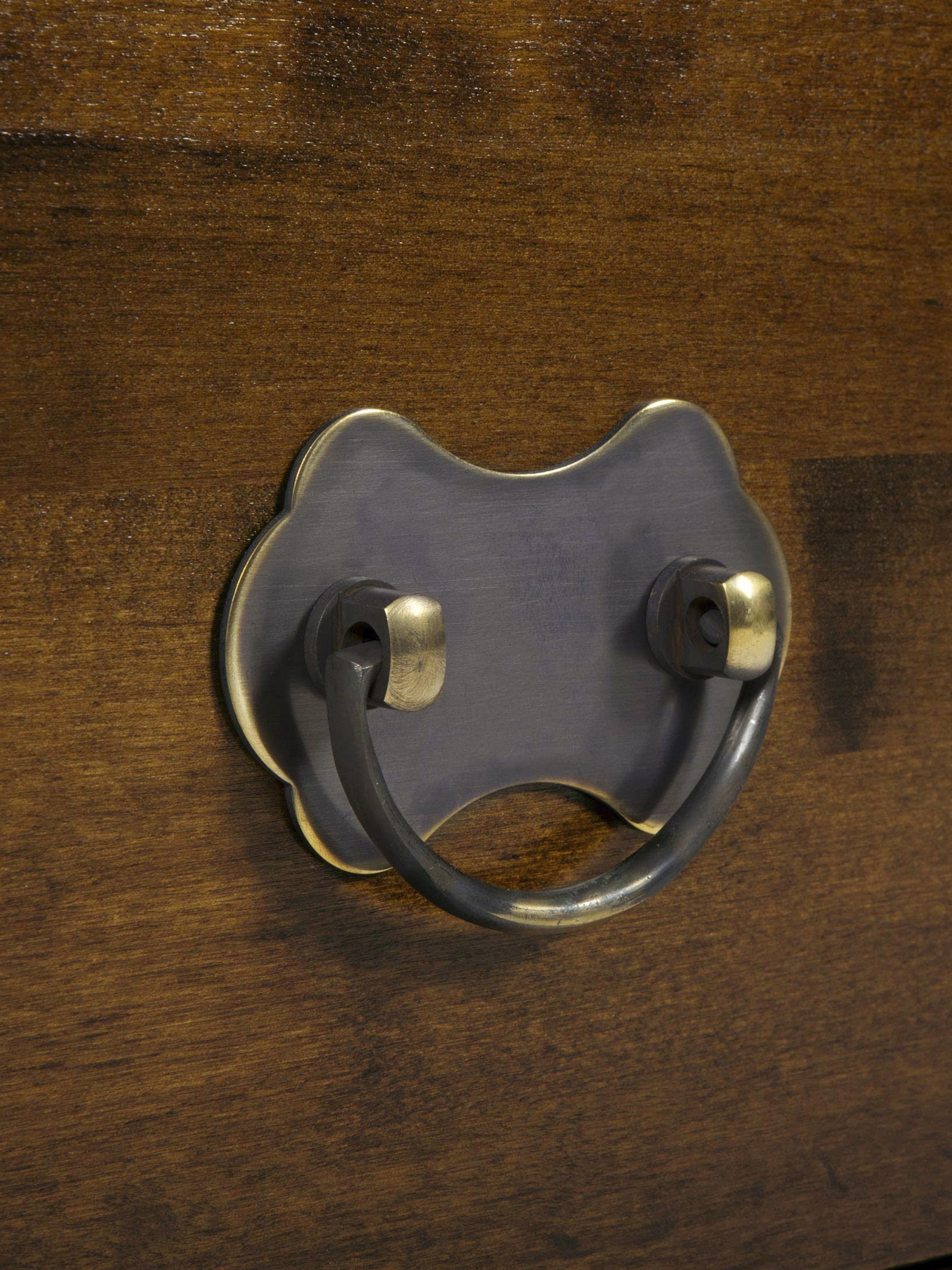 Close-up of a metal drawer pull on a wooden surface.