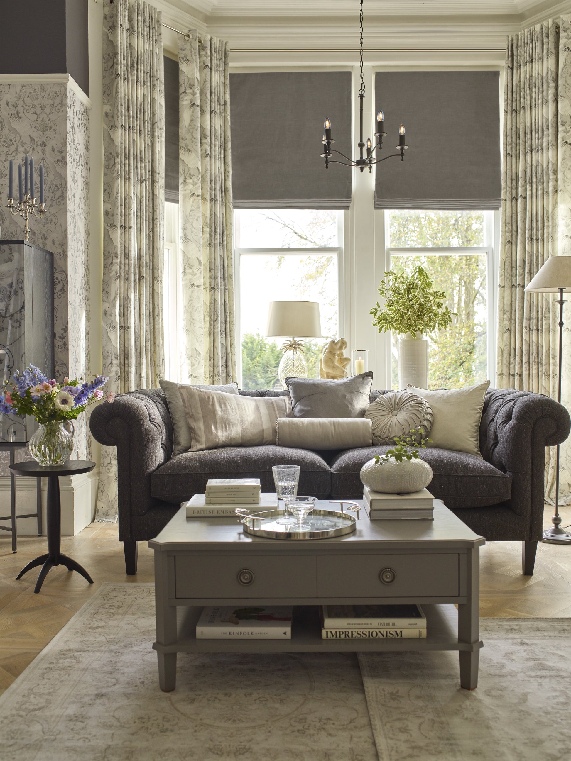 Living room with gray sofa, coffee table, and large windows.