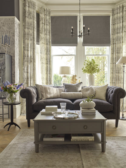 Living room with gray sofa, coffee table, and large windows.