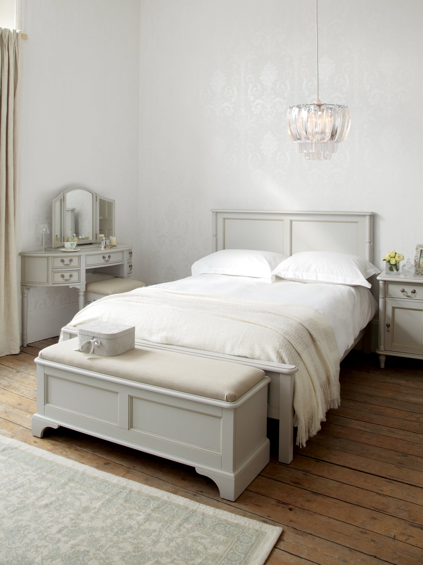 A dove grey blanket box with a cushioned top and wooden body, designed for storage and seating, situated at the end of a bed