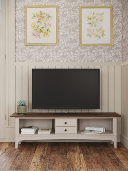 TV mounted on a wooden stand with floral wall art above in a room with wooden flooring.