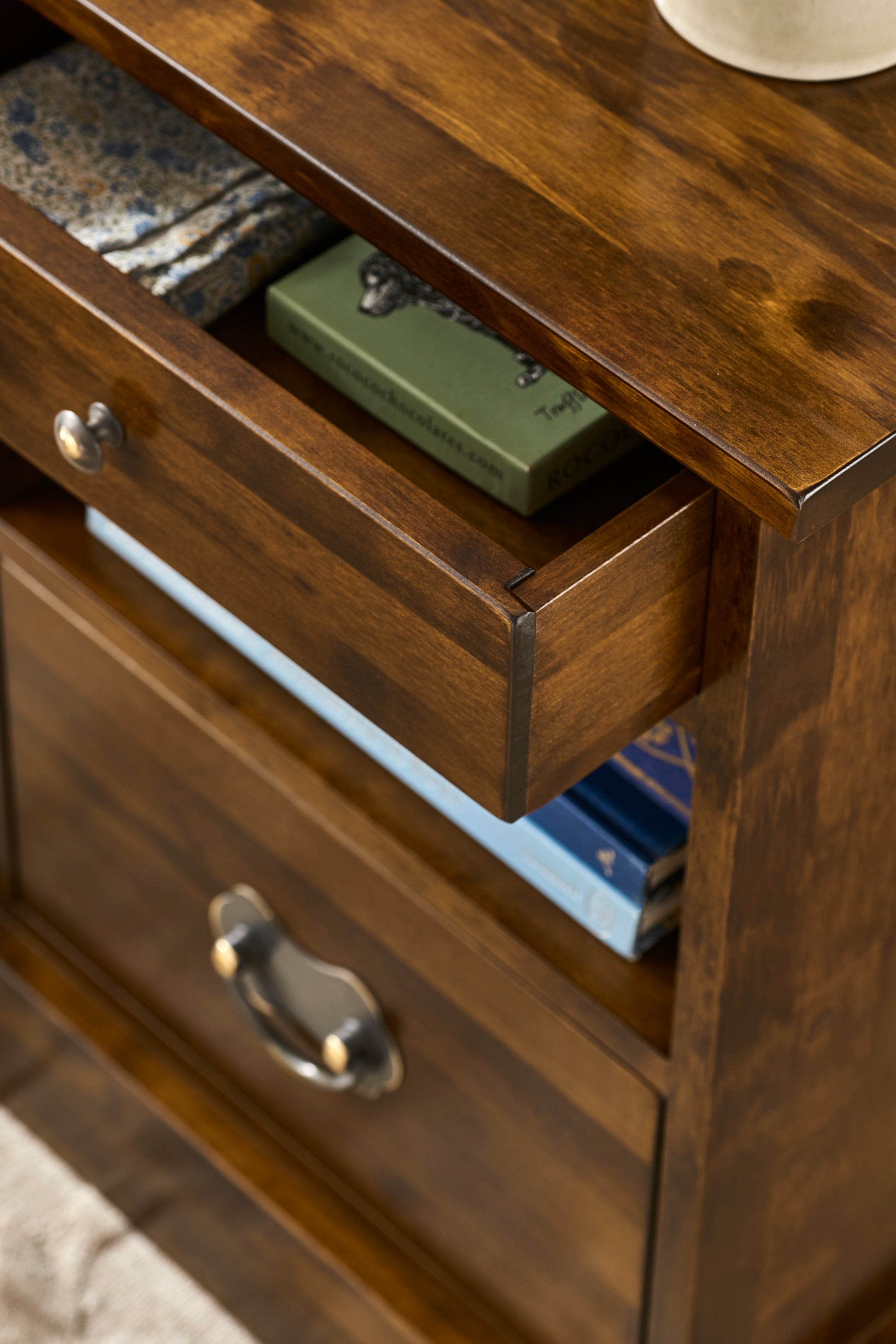 Wooden dresser with open drawer showing green item