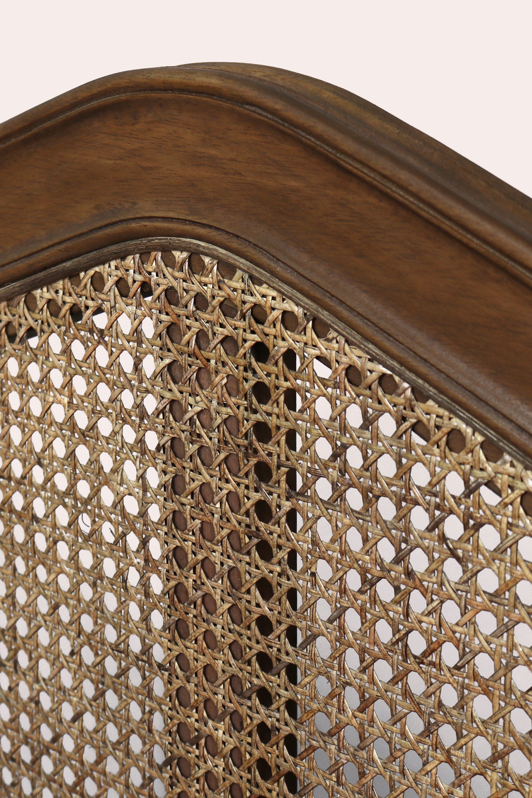 Close-up of a wooden headboard with woven cane design