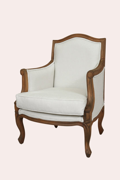 White upholstered armchair with wooden frame on a light pink background