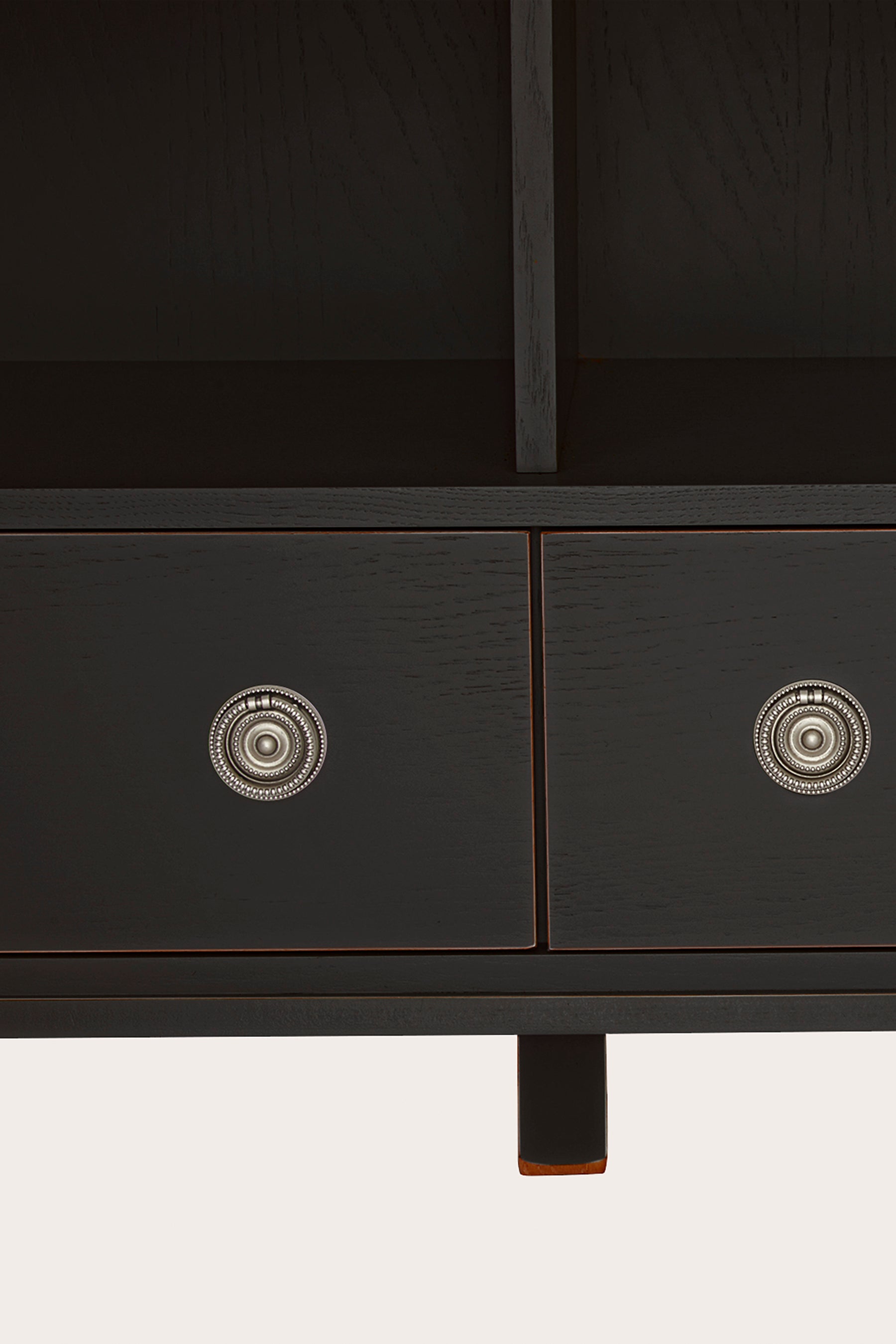 Close up of black drawers of a black bookcase with decorative silver knobs on a white background